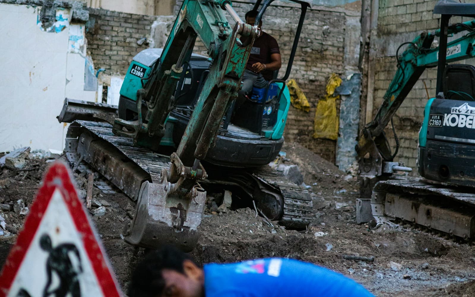 Two compact excavators working at an urban construction site